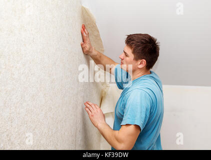 young worker smoothing wallpaper in his house closeup Stock Photo