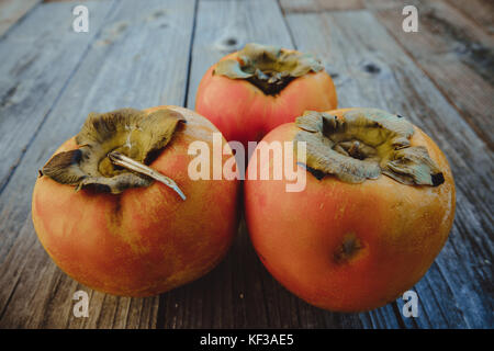 Delicious fresh persimmon fruit on a wooden board Stock Photo