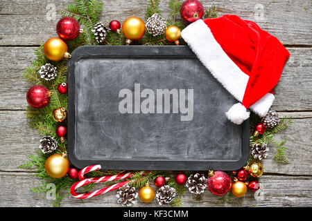 Classic christmas and new year composition chalk board, balls, toys, candy, fir branches on vintage wooden background Copy Space Stock Photo