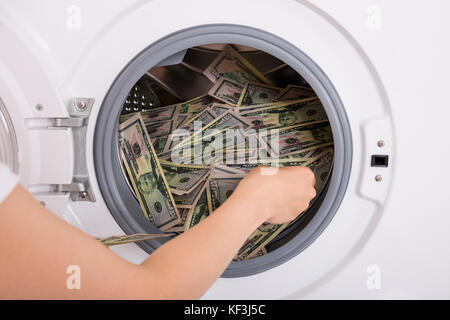 Close-up Of Person Hand Inserting Dirty Money In Washing Machine Stock Photo