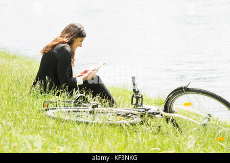 Happy Young Businesswoman Sitting Near Bicycle Using Digital Tablet Stock Photo