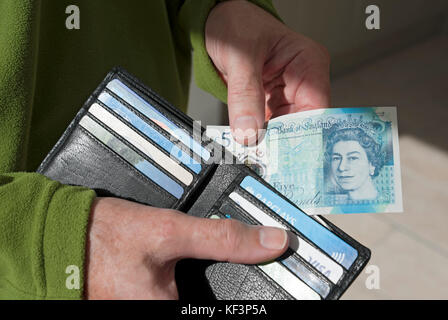 Close up of man person taking cash new £5 five pound note English money banknote banknotes from wallet England UK United Kingdom GB Great Britain Stock Photo