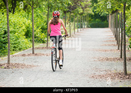 Young Female Cyclist Riding Away On Her Bicycle With Safety Helmet Stock Photo