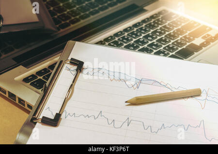business documents graph financial on  table with laptop computer and coins and diagram. Stock Photo