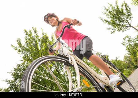 Low Angle View Of A Happy Young Female Cyclist Riding Bicycle Stock Photo
