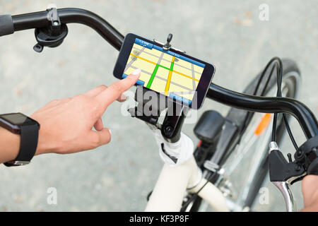 Close-up Of Human Hand Pointing At Smart Phone Showing GPS Navigation On Bicycle Stock Photo