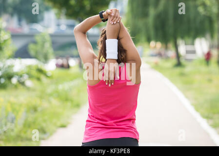 Rear View Of Sporty Young Woman Doing Morning Exercise In Park Stock Photo