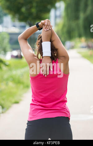 Rear View Of Sporty Young Woman Doing Morning Exercise In Park Stock Photo