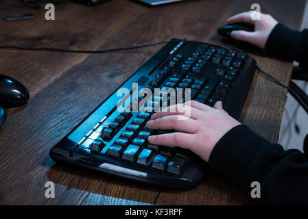 Close-up Of A Boy Using Keyboard On Desk Stock Photo