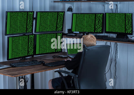 Child Using Multiple Computers With Binary Code On Screen Stock Photo