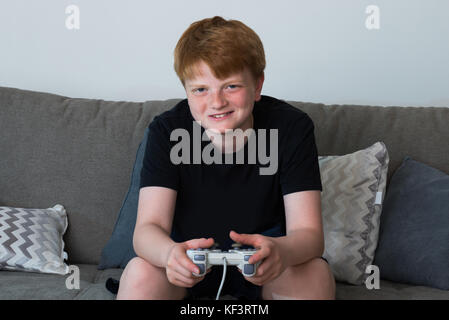 Portrait Of Happy Boy Sitting On Sofa Playing Videogames Stock Photo