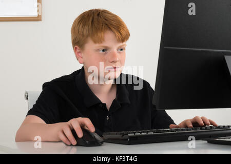 Boy Sitting On Chair Using Computer At Home Stock Photo
