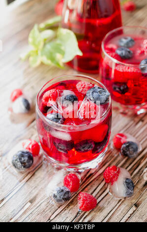Summer berry lemonade with frozen berries and a jug on a wooden rustic table, selective focus Stock Photo