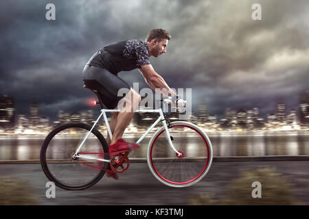 Cyclist cycling in front of a nightly skyline Stock Photo