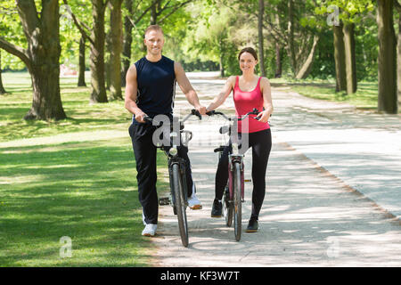 Young Happy Couple Standing With Bicycles In Park Stock Photo