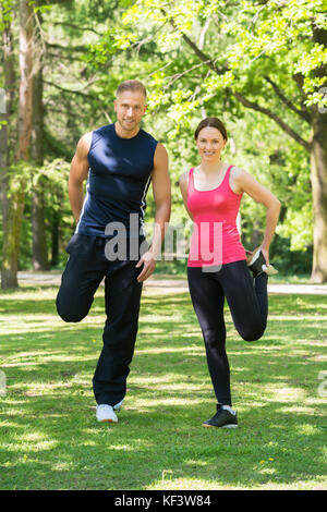 Young Happy Couple Doing Exercise In Park Stock Photo