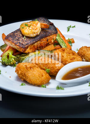 grilled shrimp and salmon filet and vegetables served with potato crochets Stock Photo