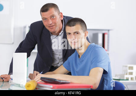 professor assisting a student with studies in college library Stock Photo