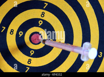 syringe hitting a bull eye on a dart board Stock Photo