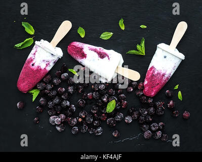 Black-currant milk ice-creams or popsicles with frozen black-currant and mint Stock Photo