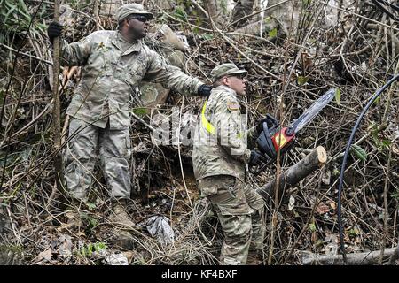 Puerto Rican National Guard officers clear fallen trees and debris from the road during relief efforts in the aftermath of Hurricane Maria September 30, 2017 in Cayey, Puerto Rico. Stock Photo