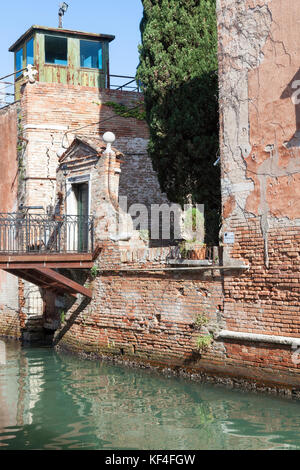 Ancient architecture on Giudecca Island, Venice,  Veneto, Italy with a small private bridge over a canal to the entrance to a walled garden in weather Stock Photo