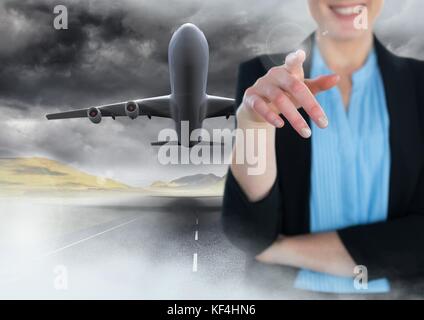 Digital composite of Businesswoman touching air in front of flying plane on runway Stock Photo