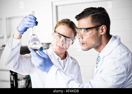 Concentrated scientists looking at beaker in laboratory Stock Photo