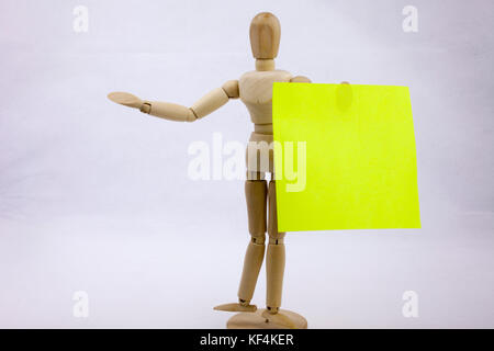 Two green sticky note reminders on a white background hoalding by the wooden sculpture with text copy space Stock Photo