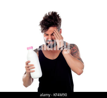 Attractive guy with headache holding a milk bottle isolated on a white background Stock Photo