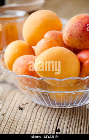 Fresh organic apricots in glass bowl on wooden board Stock Photo