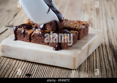 Caramel chocolate brownies with dark chocolate ganache served on marble stand Stock Photo