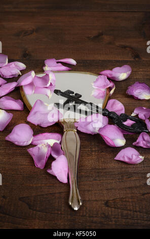 closeup mirror with pink rose petals and a key Stock Photo
