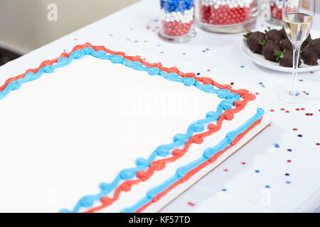 Patriotic red, white and blue cake with champagne on a table at an election campaign party with sprinkled confetti and candy in jars Stock Photo
