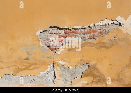 Damaged brickwall with a hole. Damaged plaster on brickwall. Old brick wall with damaged  plaster square. Stock Photo