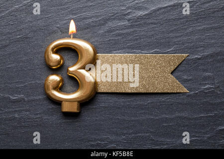 Gold number 3 celebration candle with glitter label Stock Photo