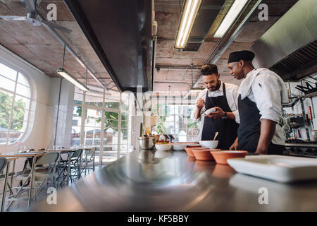 Two male chefs cooking food at kitchen in restaurant.  Professional cooks working at restaurant kitchen together. Stock Photo