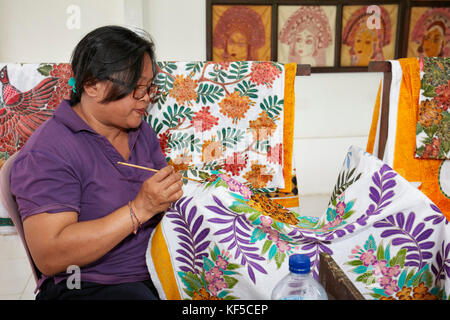 Indonesian craftswoman painting batik in a workshop. Batubulan village, Ubud area, Bali, Indonesia. Stock Photo