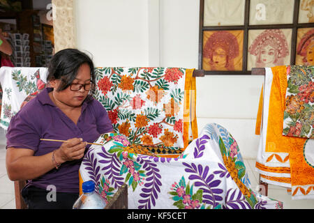 Indonesian craftswoman painting batik in a workshop. Batubulan village, Ubud area, Bali, Indonesia. Stock Photo
