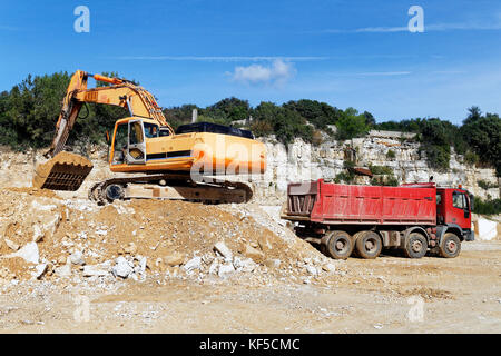 Excavator loading sand into dump truck Stock Photo
