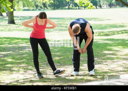 Photo Of Exhausted Young Couple Standing In Park Stock Photo