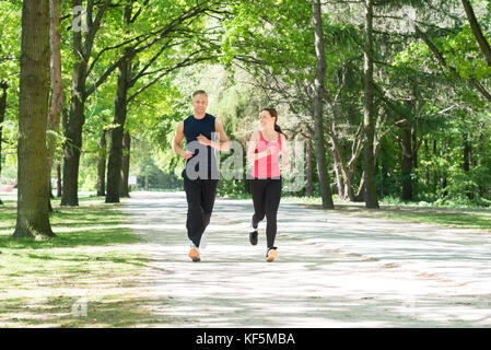 Running young couple in shadows with sun light behind them while