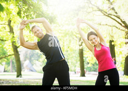 Photo Of Young Couple Exercising Together In Park Stock Photo