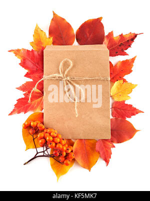 Craft paper gift envelope flat lay on red and yellow autumn leaves isolated on white background. Top view. Stock Photo