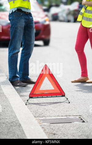 Young Couple Calling For Service On Mobile Phone With Broken Down Car On Street Stock Photo