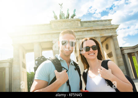 Young Happy Couple Standing In Front Of Brandenburg Gate Stock Photo