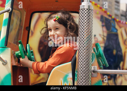 Cute little girl ride on a children's train and smiles happily Stock Photo