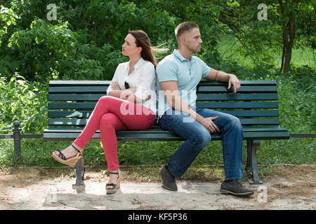 Unhappy Couple Sitting Back To Back On Bench In Park Stock Photo