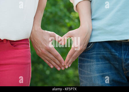 Close-up Of Couple Hand Making Heart Shape Stock Photo