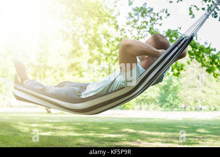 Young Man Relaxing In Hammock At Park Stock Photo